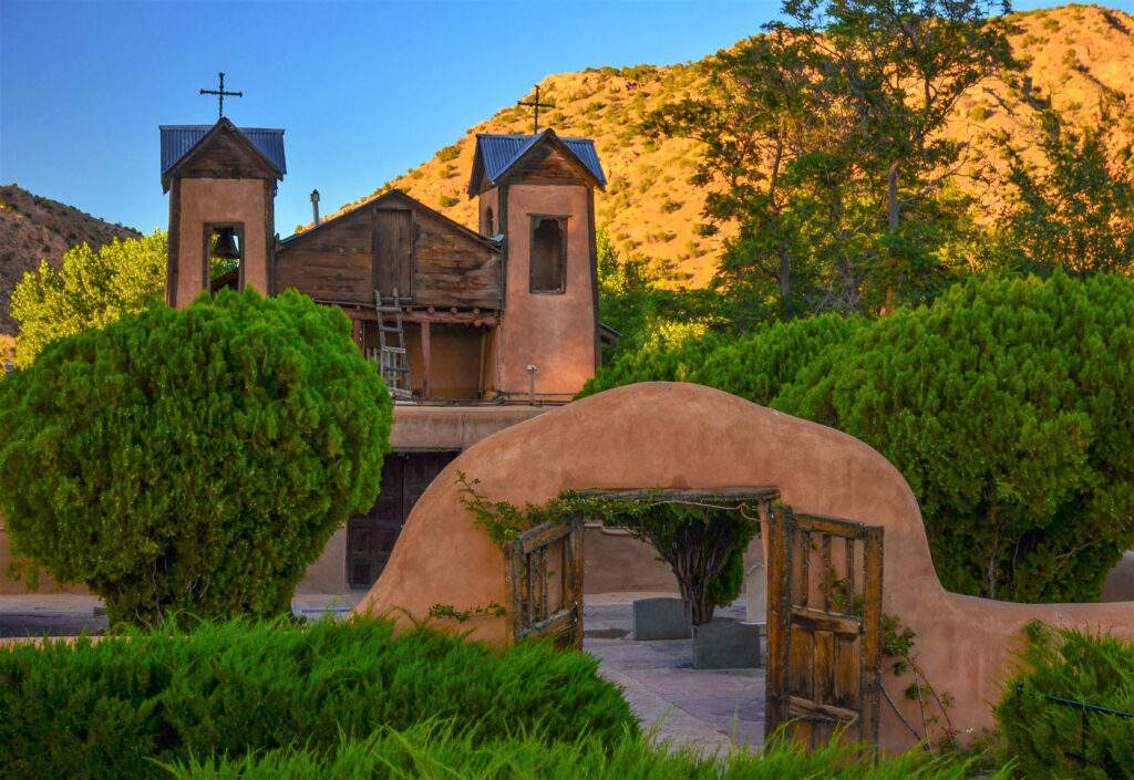 Historic church in Chimayo surrounded by greenery and trees